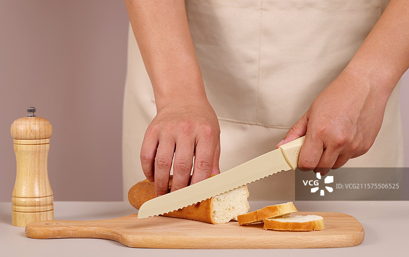 穿着围裙的人 拿着面包刀切面包图片素材