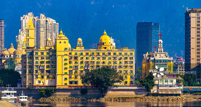 青蓝色硕大鼓山峰前摩天楼簇拥金黄色温馨暖和富有意大利威尼斯建筑风格的福州闽江中四面环水中洲岛基督教堂图片素材