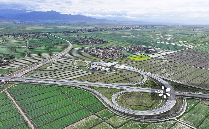 2025年6月21日，在甘肃省张掖市民乐县境内，蜿蜒曲折的高速公路与乡村田园、青山河流相映成景。图片素材