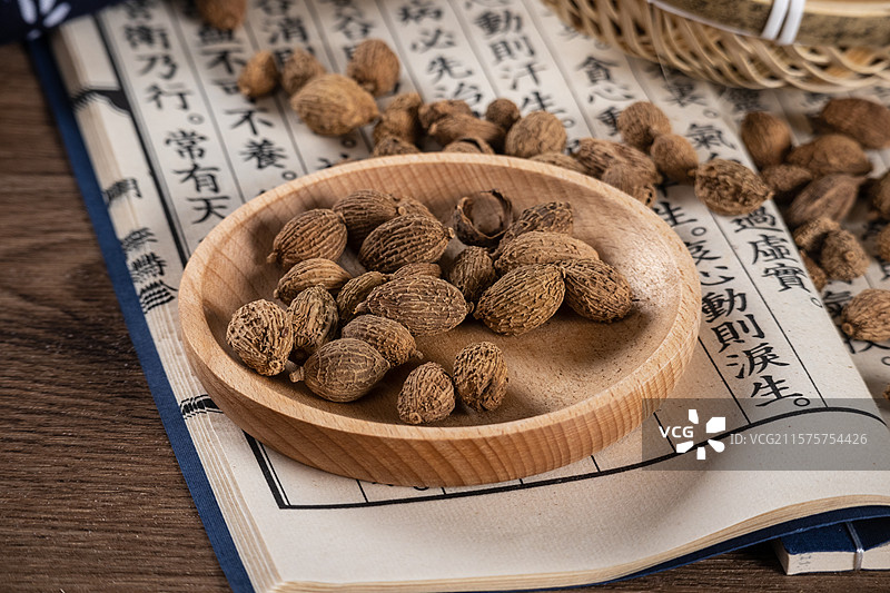 古风背景桌面上竹编篮子里摆放着晾晒干的砂仁中药药材图片素材