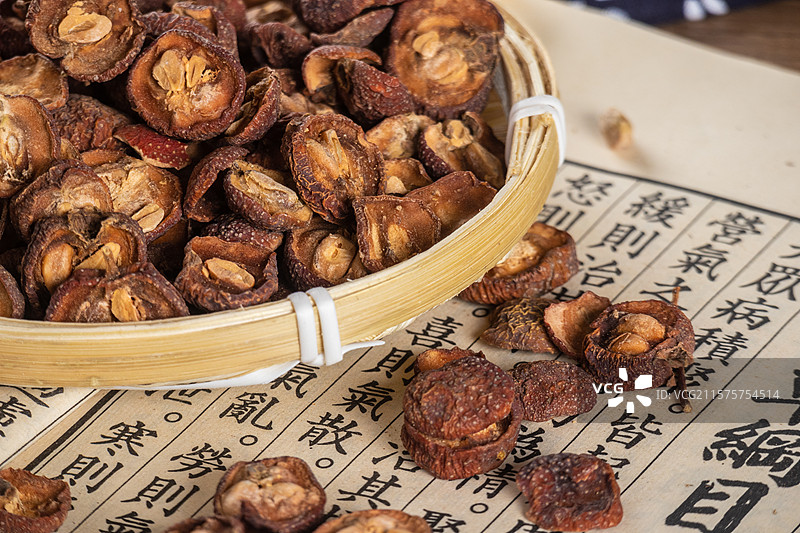 古风背景桌面上竹编篮子里摆放着晾晒干的山楂中药药材图片素材