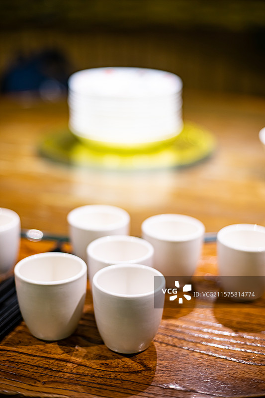 中国餐饮餐厅饭店饭馆行业，空的餐桌拍摄主题，中国传统木制圆桌上的叠起来的茶碗餐具，室内无人图像摄影图片素材