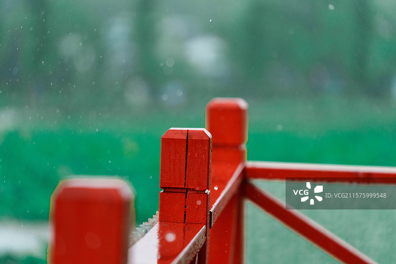 朦胧雨景下的红色木制栏杆图片素材