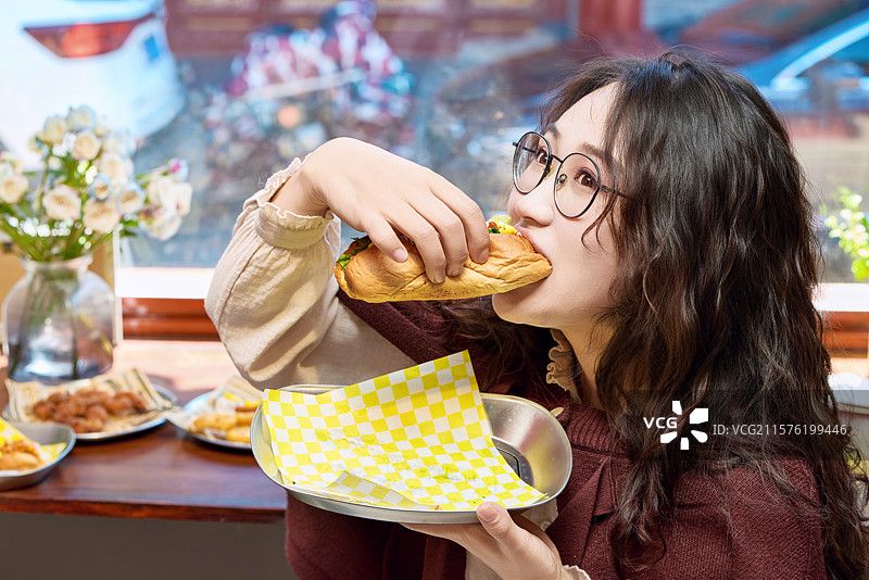 在没事热狗快餐店大吃特吃的东方女性图片素材