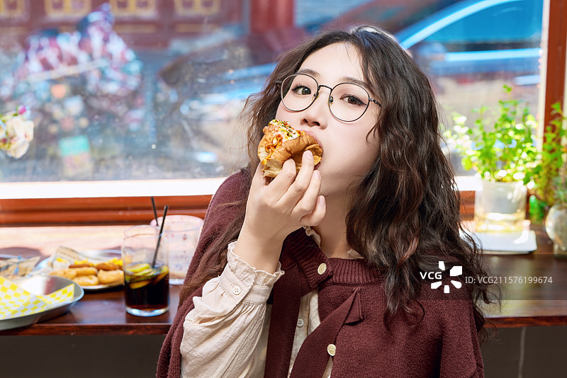 在没事热狗快餐店大吃特吃的东方女性图片素材
