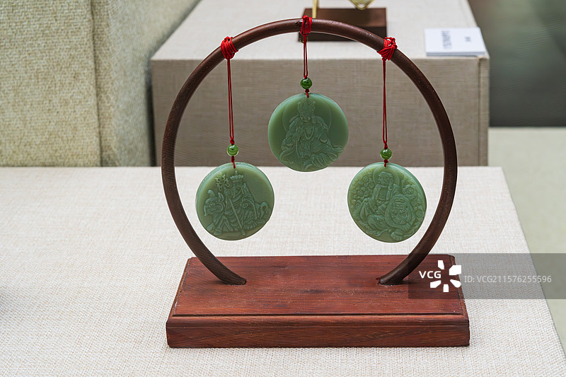 三件翡翠挂件展示于木质支架上图片素材