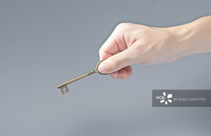 一只手拇指和食指捏住一把古铜老钥匙图片素材