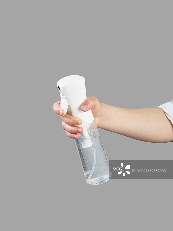 灰色背景下手拿喷雾器展示图片素材