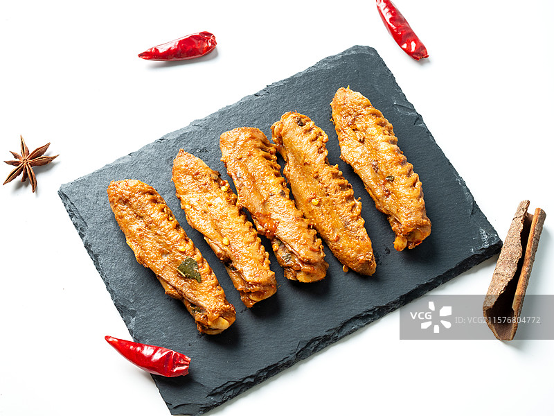 放置在黑石板上的卤鸭翅图片素材