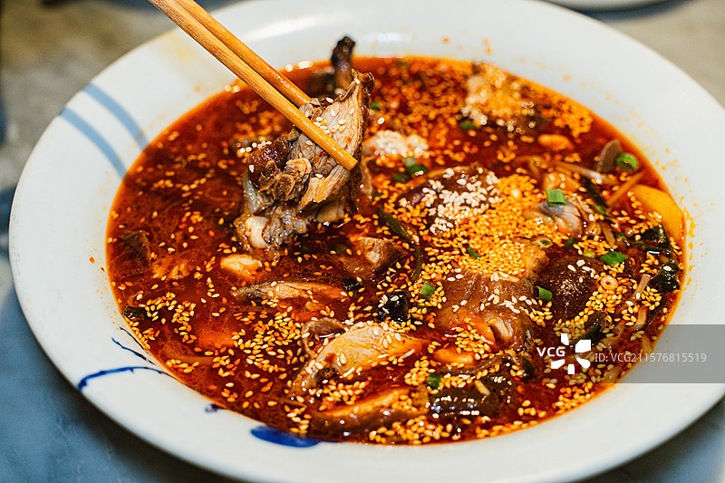 静物美食，从中国传统川菜冒菜中夹出烤鸭的特写图片素材