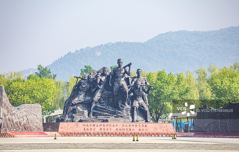 山东泰安泰山天平湖风景区绿水青山背景中的泰山挑山工雕塑建筑特写镜头图片素材