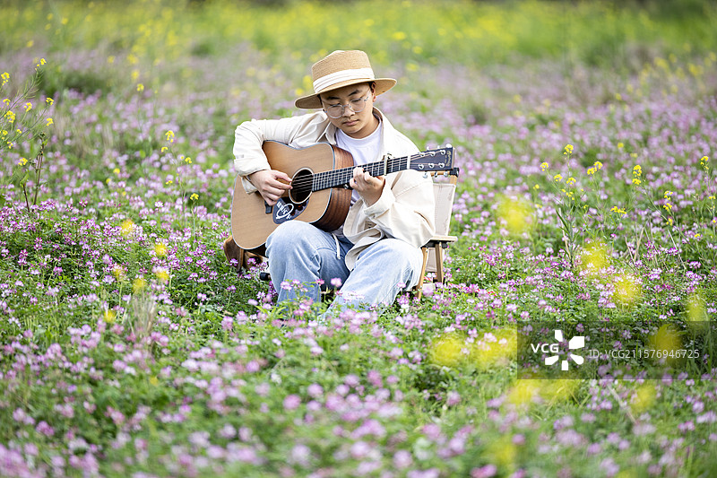 坐在花丛中弹吉它的小男孩图片素材