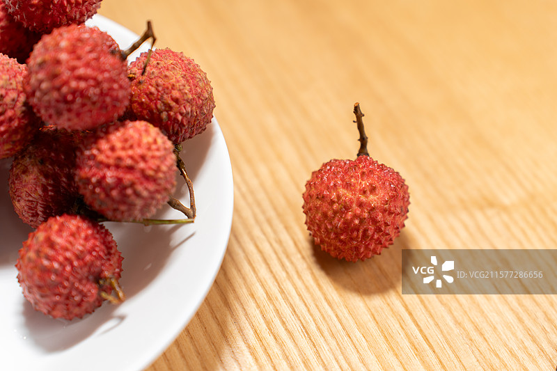 夏日的新鲜荔枝放在木纹桌面上图片素材