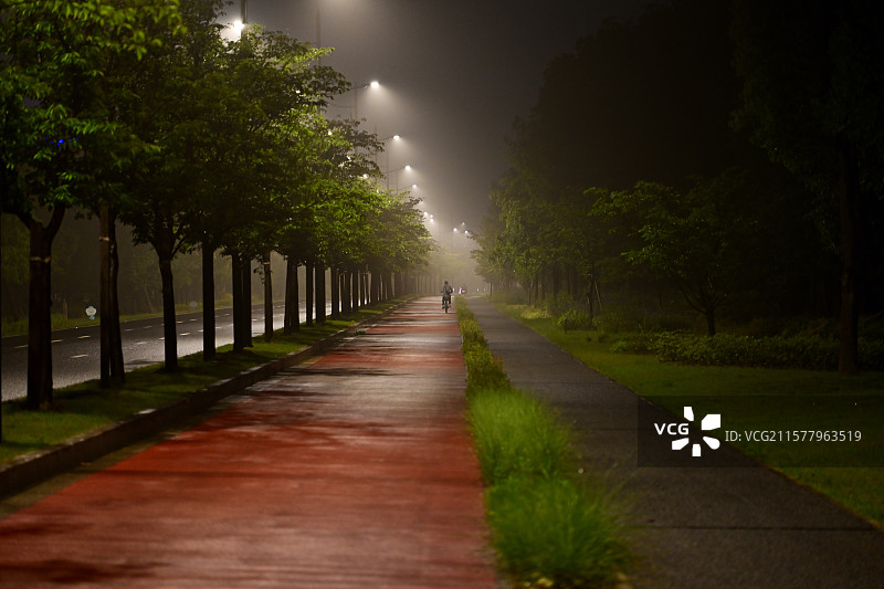 梅雨季的路灯和行人，健康生活方式，锻炼，雨夜中的上海奉贤望园路图片素材