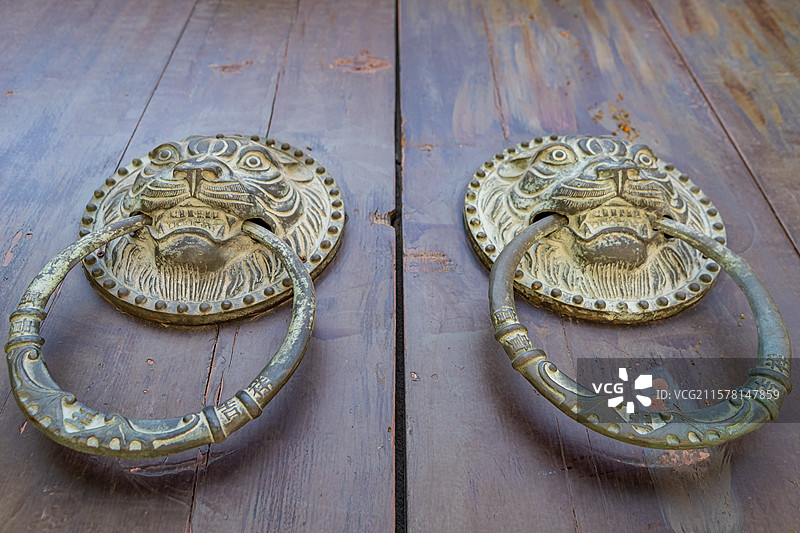 中国传统房屋建筑拍摄主题，古老的寺庙宫殿大殿古代建筑上，褐色木门上狮子虎头门环，户外白昼无人图像摄影图片素材