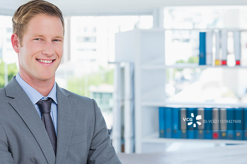 阳光透过大窗户洒入，照亮了办公桌上的笔记本电脑和书架上的文件夹。图片素材