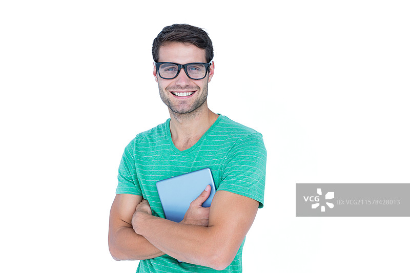 男子在工作室里微笑，手持平板电脑，穿着绿色条纹T恤和眼镜。图片素材