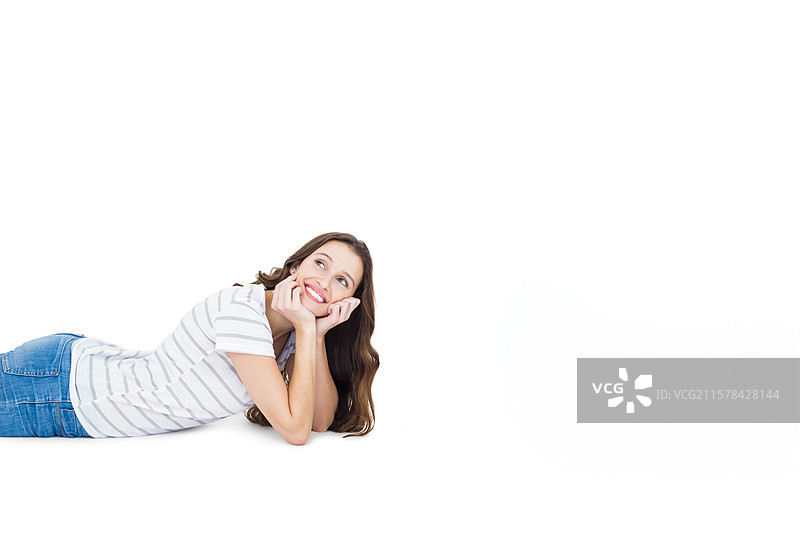 穿着条纹上衣和牛仔裤的女人趴在肚子上，托着下巴，工作室背景，留有空白空间图片素材