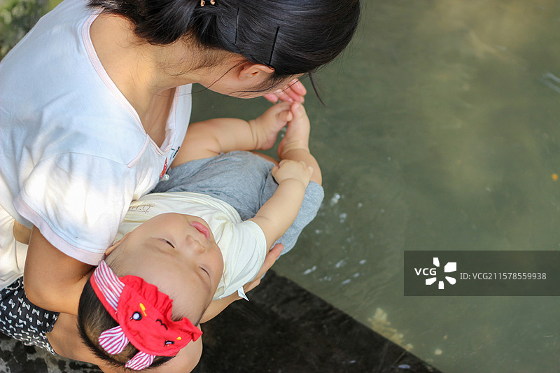 母亲抱着六个月大的婴儿在成都三道堰河流中洗脚图片素材