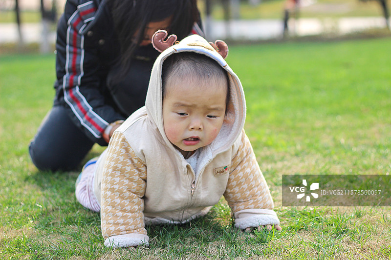 母亲带着一岁的儿子在重庆中央公园草坪上玩耍图片素材