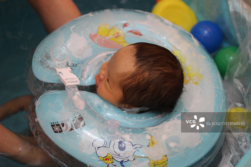 二十五天的新生婴儿戴着游泳圈泡澡图片素材