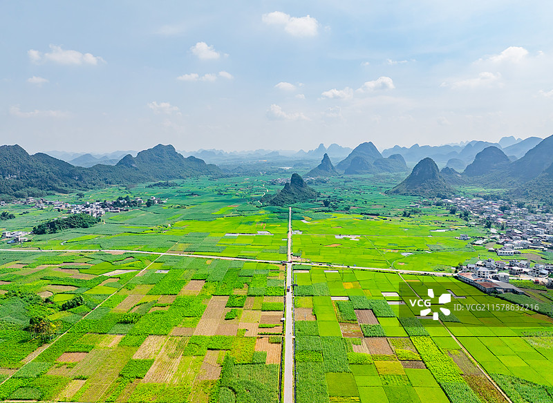 广西柳州柳城县古砦田村广阔的水稻田、喀斯特地貌、笔直的前进道路与晴朗的蓝天白云航拍视角风光图片素材