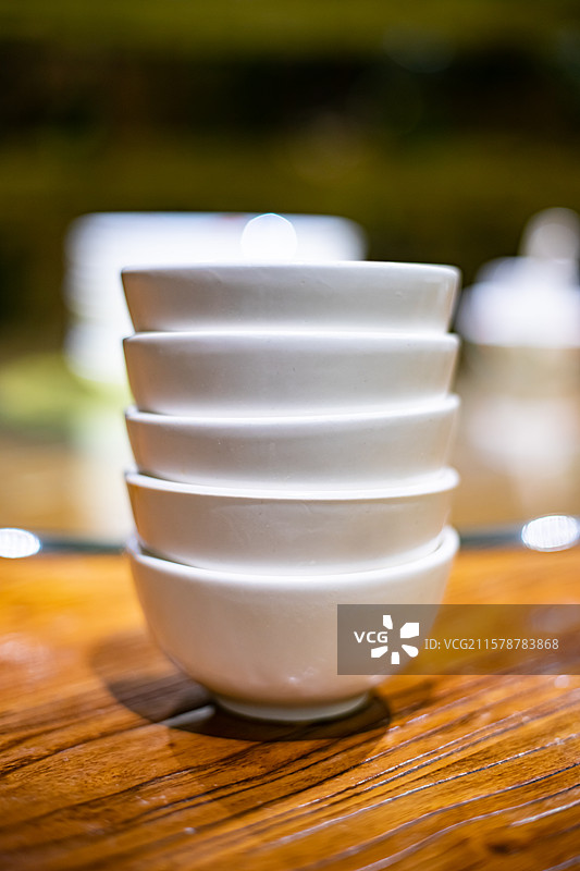 中国餐饮餐厅饭店饭馆行业，空的餐桌拍摄主题，中国传统木制圆桌上的叠起来的茶碗餐具，室内无人图像摄影图片素材