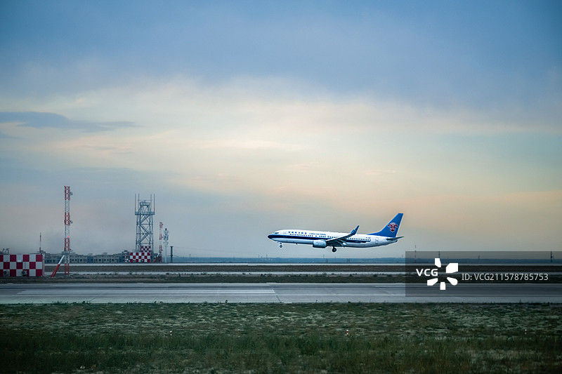 乌鲁木齐天山机场跑道上，一架航班在黄昏中腾空而起，起飞的瞬间特写图片素材