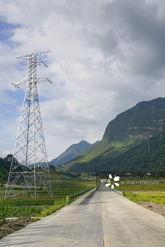 高山峡谷间的电力铁塔和无人无车乡间道路图片素材