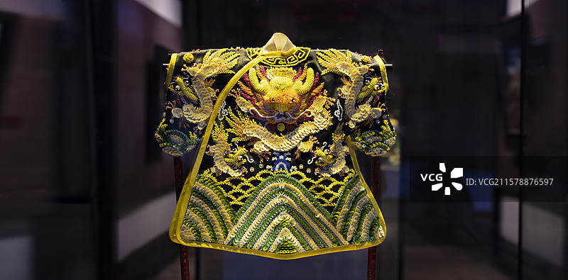 暗黑色梦幻背景前金黄色飞龙在胸怀黑底色下摆绣海浪靓丽富贵多彩色调斑斓珠绣龙袍彰显威严夺人眼球令人惊艳图片素材