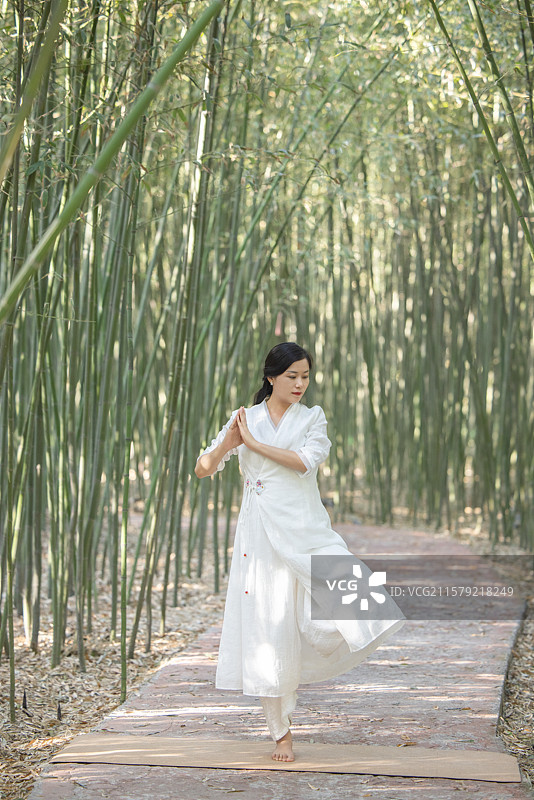 年轻女人在竹林中做瑜伽图片素材