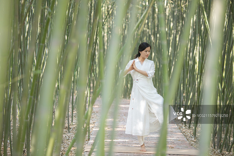 年轻女人在竹林中做瑜伽图片素材