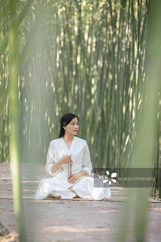 年轻女人在竹林中做瑜伽图片素材