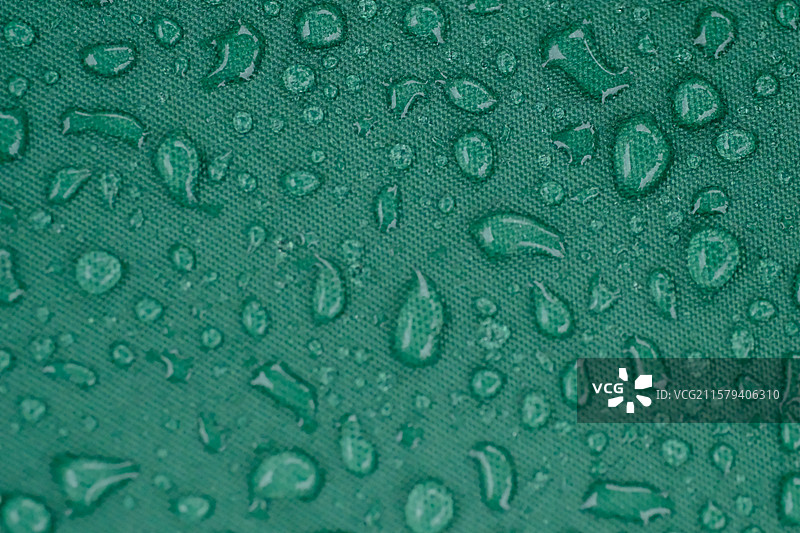 夏天下雨天。绿色伞面上的雨滴。高清绿色背景图图片素材