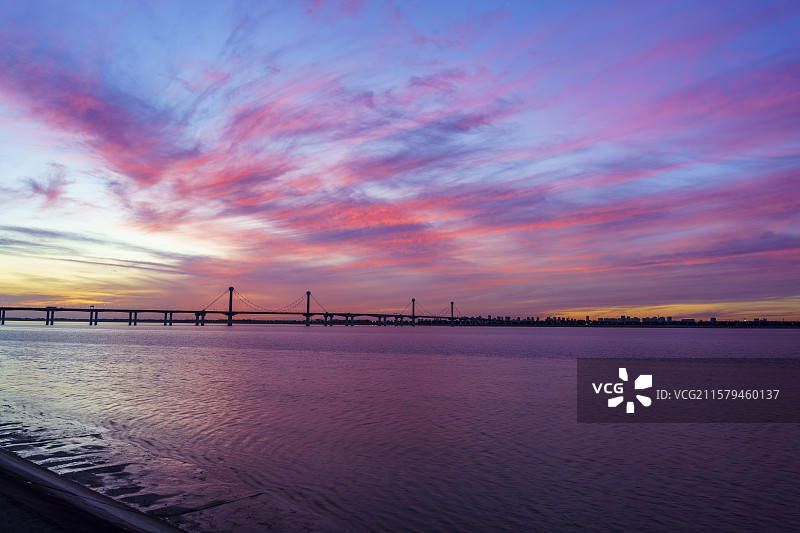 杭州钱塘江江东大桥畔，炽烈的火烧云染红天际，江面倒映壮观霞光。图片素材