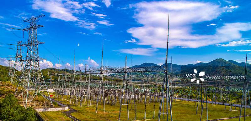 蓝天白云下丘陵山脉旁铁塔林立雄伟壮观规整有序的输变电枢纽站图片素材