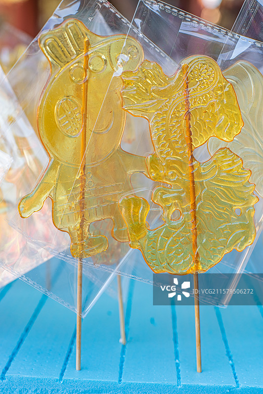 中国传统文化手艺拍摄主题，一排包装好的老虎山羊奥特曼熊二小猪佩奇孙悟空糖画，户外无人白昼图像摄影图片素材