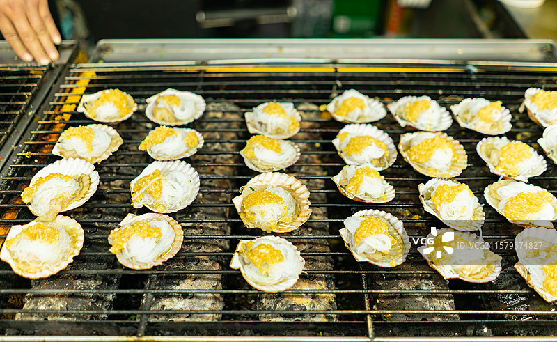 中国餐饮行业饮食产业传统经典中国食品，美食拍摄主题，铁丝网烤肉架上的烧烤生蚝特写，户外夜晚无人图像图片素材