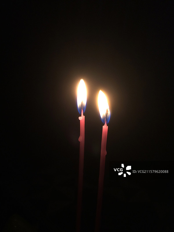 两只燃烧的红色生日蜡烛，黑色背景图片素材