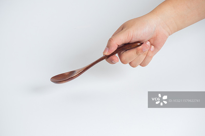 白色背景里一只手拿着木勺子特写图片素材