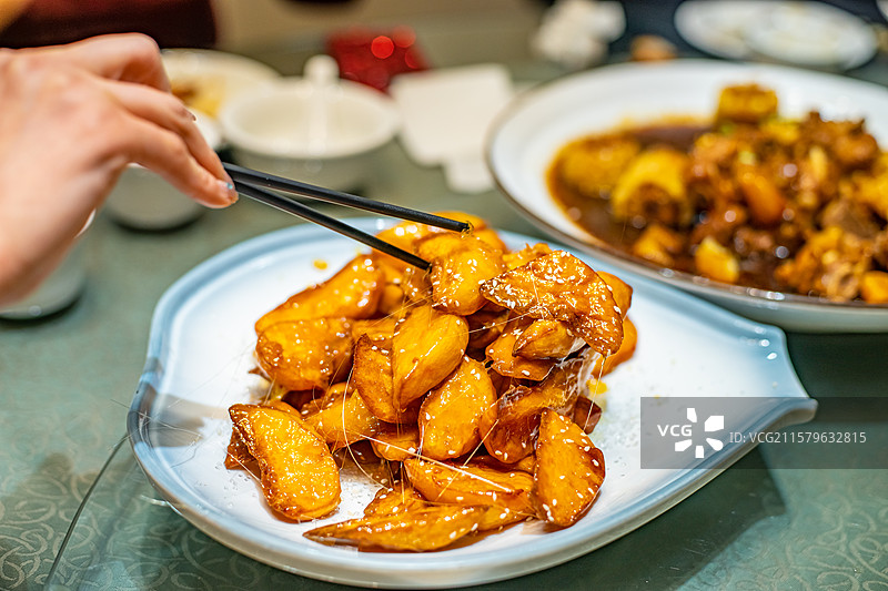 中国餐饮行业饮食产业，传统经典中国食品，一盘子正在拉丝的拔丝地瓜拔丝山药，室内无人图像图片素材