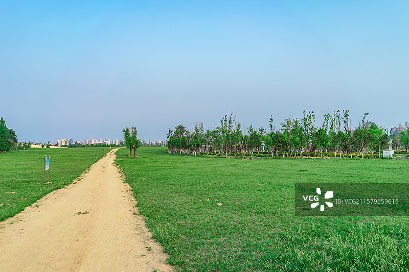 中国非都市风光拍摄主题，绿色的草坪，蓝色的天空和黄色的土路主干道，户外白昼无人图像摄影图片素材