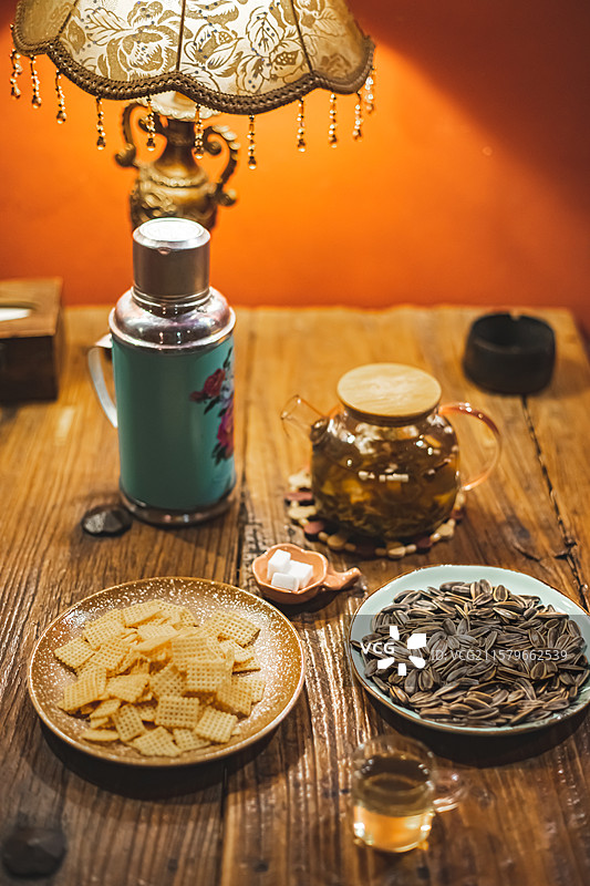 中国休闲娱乐健康生活方式拍摄主题，木制桌子上一堆黄色的锅巴瓜子小吃暖水壶和玻璃杯，室内无人图像摄影图片素材