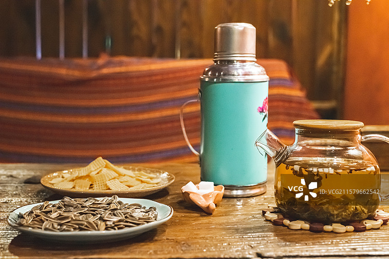 中国休闲娱乐健康生活方式拍摄主题，木制桌子上一堆黄色的锅巴瓜子小吃暖水壶和玻璃杯，室内无人图像摄影图片素材