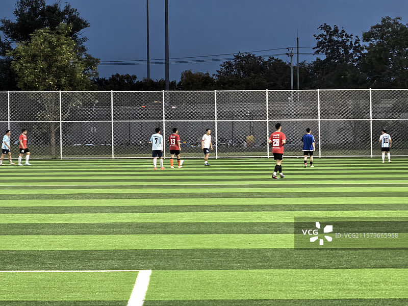 夜晚灯光下球场上踢足球的人图片素材