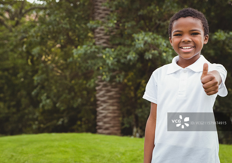非裔美国儿童在阳光明媚的公园里，绿草如茵的草坪旁，竖起大拇指，旁边有棕榈树，留有空白空间。图片素材