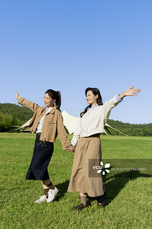 在户外露营基地享受自由感觉的两个年轻女子图片素材