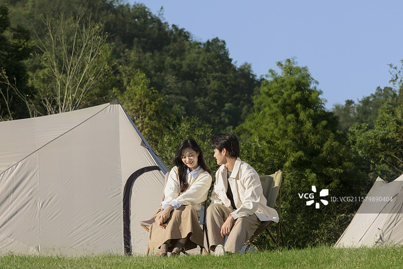 坐在帐篷前休闲聊天的年轻情侣图片素材