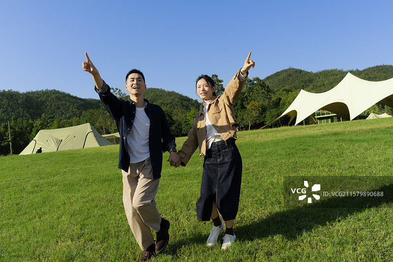 手牵手在露营地散步的年轻情侣图片素材