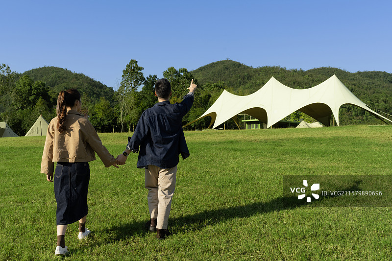 手牵手在露营地散步的年轻情侣图片素材